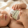 Baby holding the Amra Baby cream airless pump jar