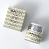 Face cream airless pump jar resting next to its green patterned box