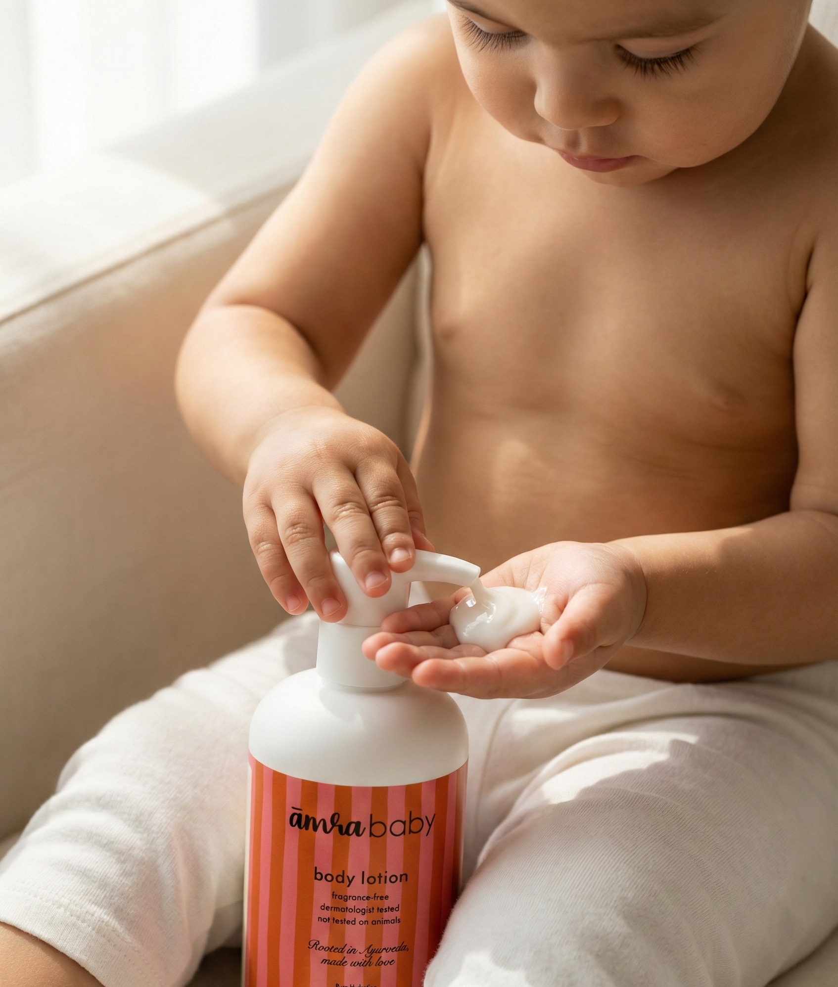 Infant applying Amra Baby fragrance free baby body lotion to their hands